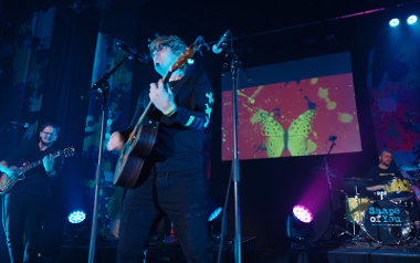 Shape of You's Daniel East singing on stage and playing the guitar